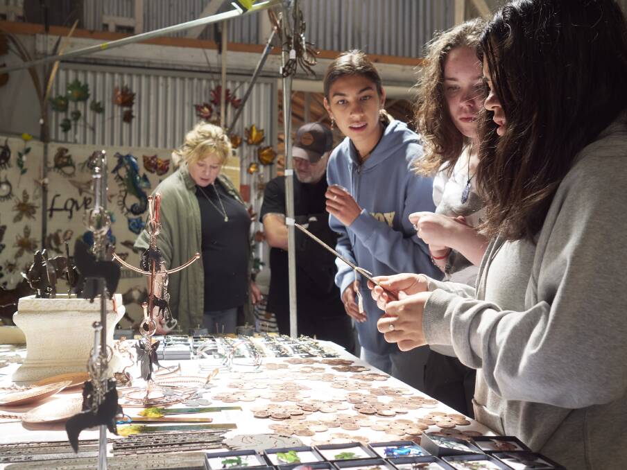 Miley Atkinson, Laura Douglas and Jasmine Gale of Hobart, examine the work of the Tasmanian Copper and Metal Art Gallery, Deloraine Craft Show. Picture by Rod Thompson 