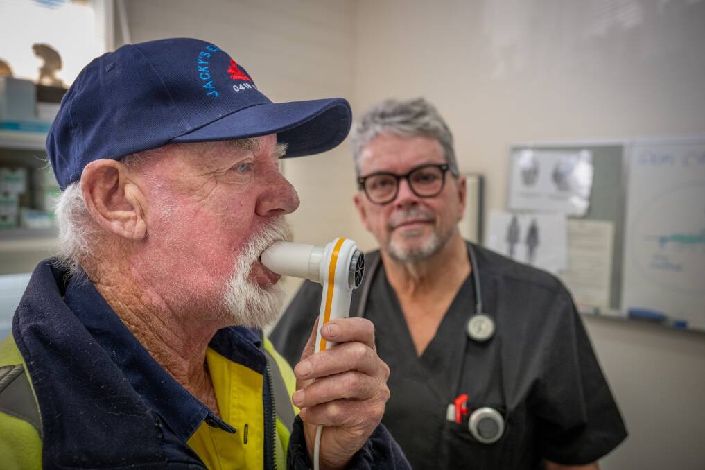 Graeme Blyth blows into the tool used in a lung capacity test at Dr Andrew Jackson's office. 