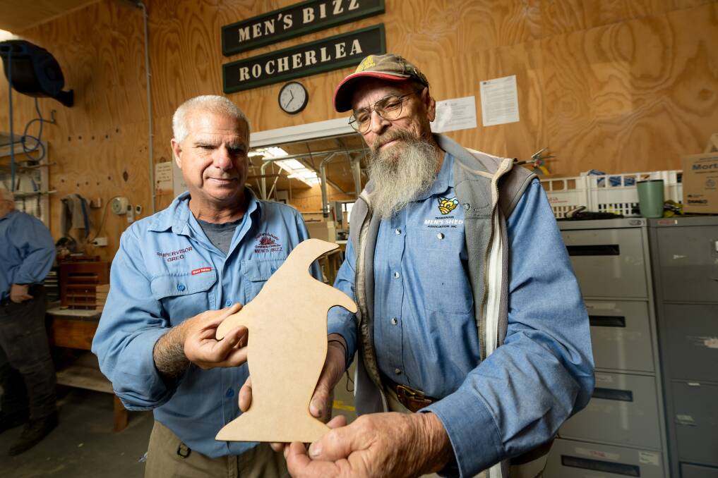 Shed co-ordinator Greg Mallett holds a penguin cut-out with Tasmanian Men's Shed Association representative Johan 'Bear' Scheer. Picture by Phillip Biggs