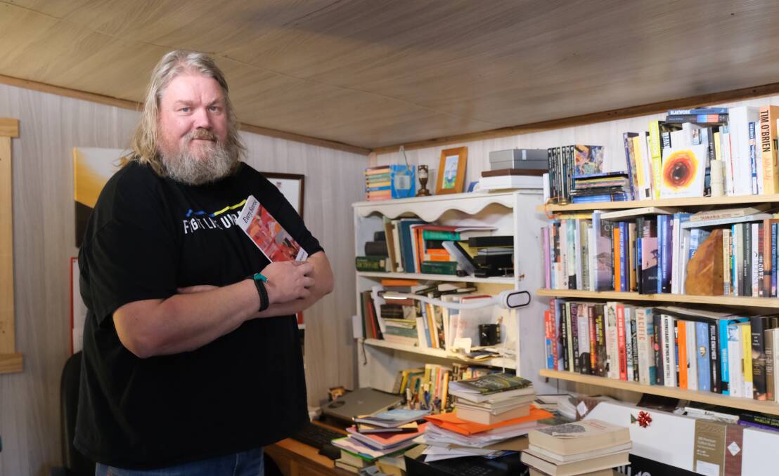 Launceston writer Cameron Hindrum in his writers studio with his new poetry collection, Every Sunrise. Photo by Declan Durrant