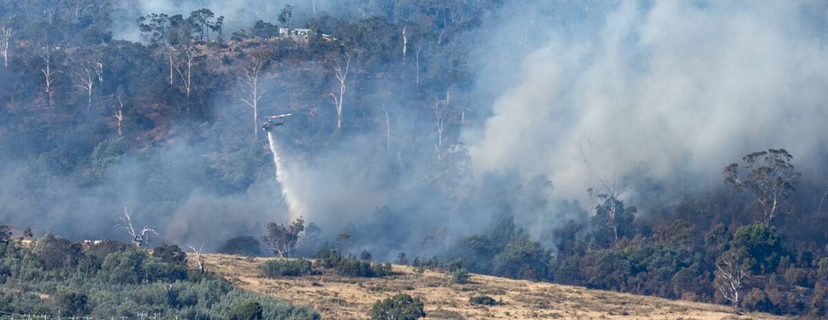 Bushfire at Russell Plains Road, Rocherlea, Launceston. 6:05 PM : Water bombing helicopters drops water onto the fire ground at Russell Plains Road. Picture by Paul Scambler