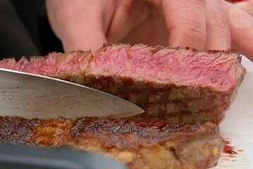 George cuts into Ben's steak to see how well it's cooked. 